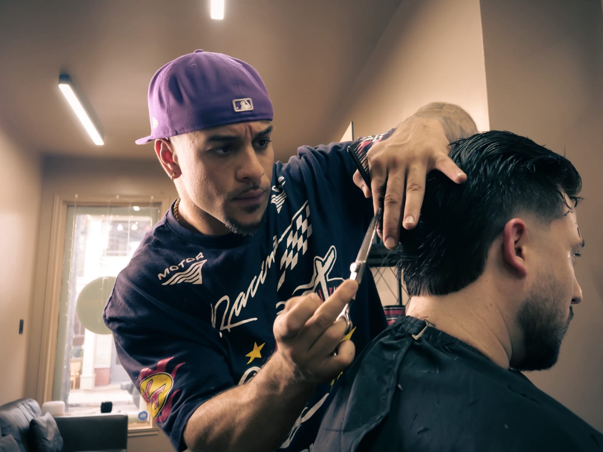 Barber cutting hair with scissors at Bona Fide
